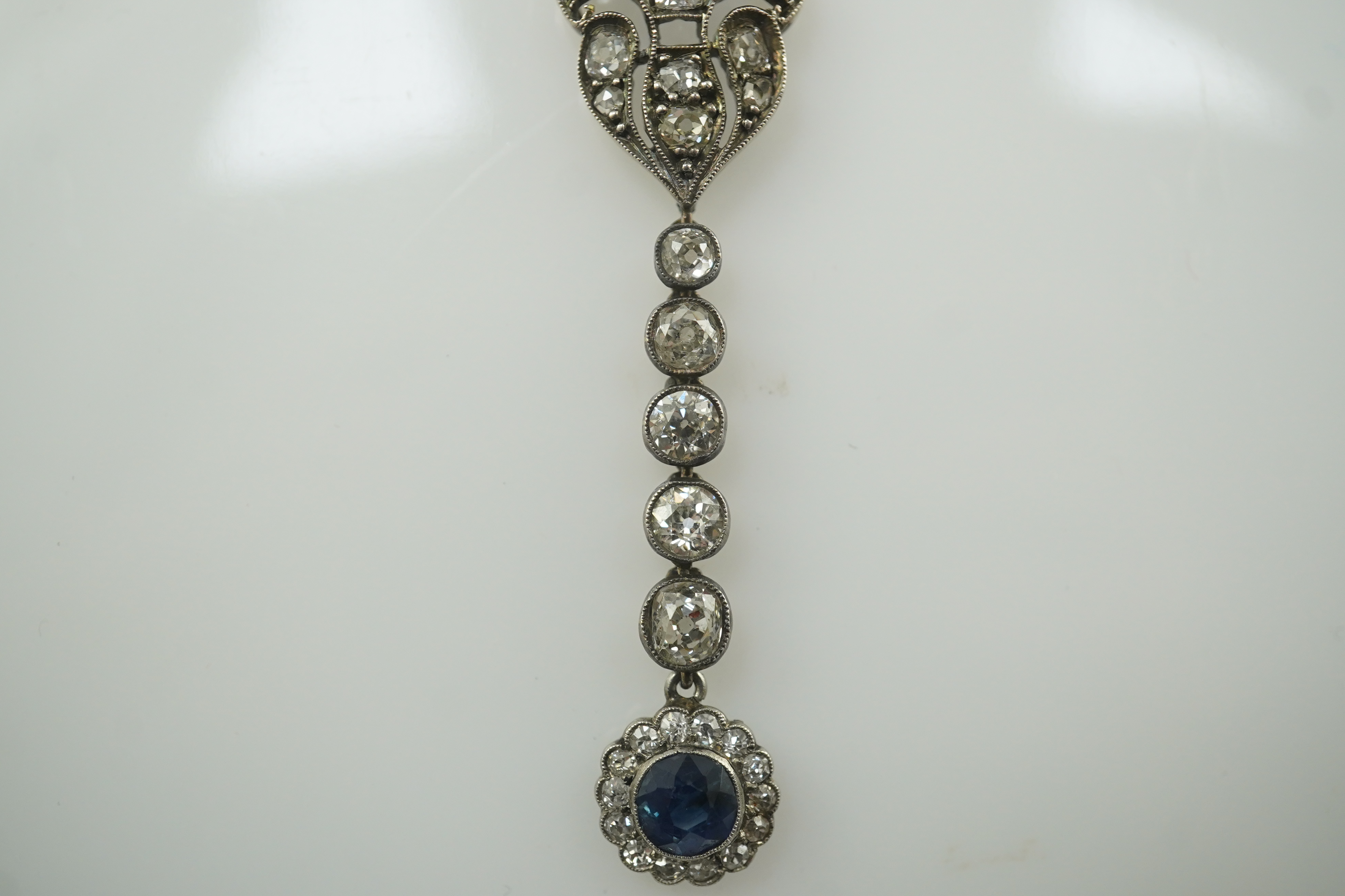 A Belle Epoque gold and silver, millegrain set sapphire and diamond cluster set drop pendant necklace